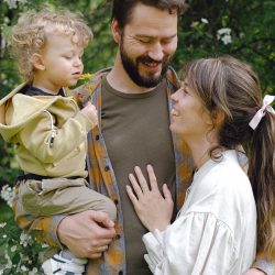 A joyful family moment captured in a Spring garden, featuring a child with parents embracing.